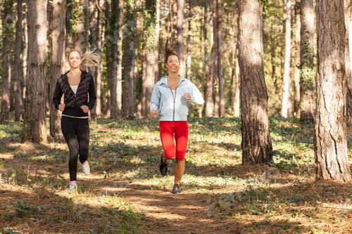 Preview: Two beautiful young women running through the park. Selective focus on brunette.