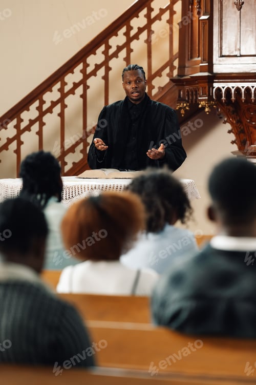 Preview: Young priest giving sermon from the pulpit to parishioners
