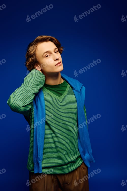Preview: Fashionable young man showcases modern style against vibrant blue backdrop