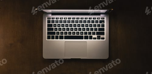Preview: Top view of a laptop on a dark table, glowing screen.