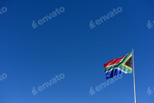 Preview: South African flag on flagpole against clear blue sky