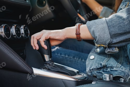 Preview: Closeup image a female driver shifting automatic gear stick while driving car