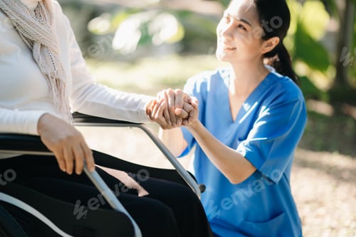 Preview: Elderly asian senior woman on wheelchair with Asian careful caregiver and encourage patient