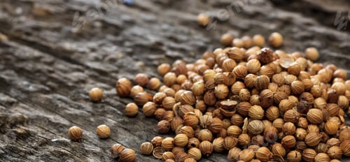 Preview: Dried coriander seeds in a pile set on old wooden surface.