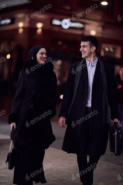 Preview: Happy multicultural business couple walking together outdoors in an urban city street at night near