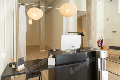 Preview: Minimalist reception desk with paper lamps in a modern studio.