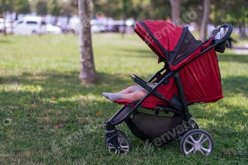 Preview: Little baby wearing socks sleeping in comfortable carriage in shady summer park on warm day