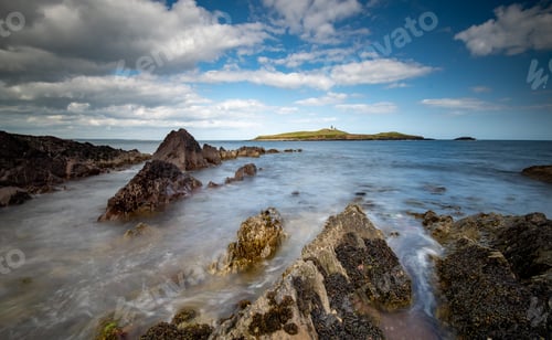 Preview: Bellycotton rocky coastline with lighthouse for marine safety in Ireland.