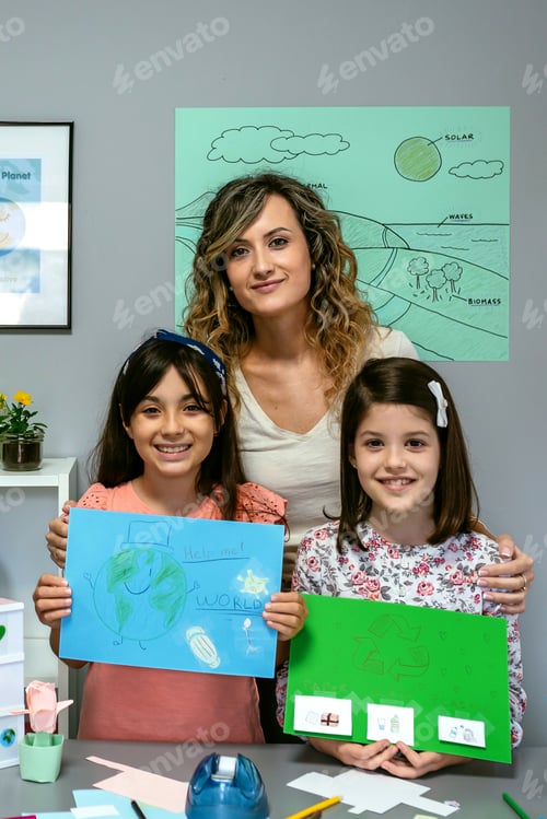 Preview: Teacher in classroom looking at camera next to students showing colorful ecological drawings