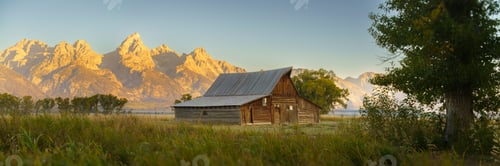 Preview: View of a rustic barn with the Grand Teton mountains in the background during sunset