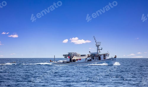 Preview: Fishing boat return. Trawler sails in Aegean rippled sea, blue sky background. Cyclades Greece.