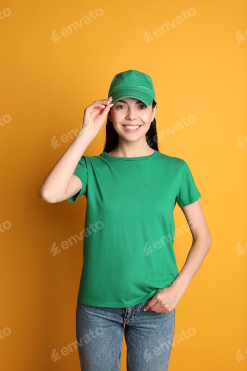 Preview: Young happy woman in green cap and tshirt on yellow background. Mockup for design