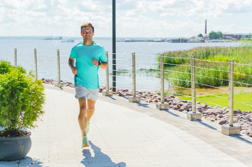 Preview: A man jogging along a scenic waterfront path under a bright sky, exuding energy and vitality.