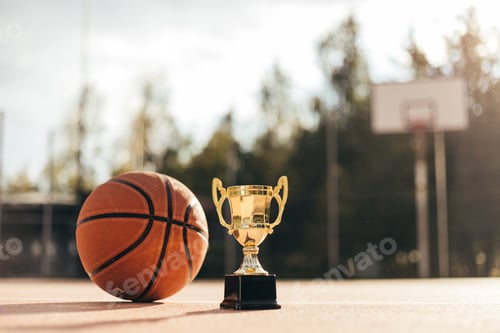 Preview: Basketball ball and golden cup on rubber playground close up, street basketball competition