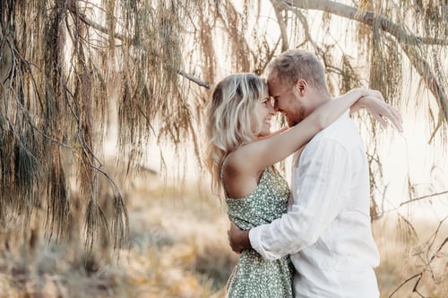 Preview: Affectionate Couple Embrace Under Tree with Dappled Light