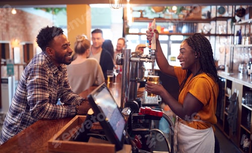 Preview: Smiling Female Bartender Behind Counter Serving Female Customer With Beer
