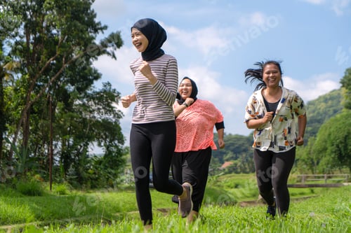 Preview: Happy Asian Women Jogging Together Outdoors in Lush Green Nature Setting