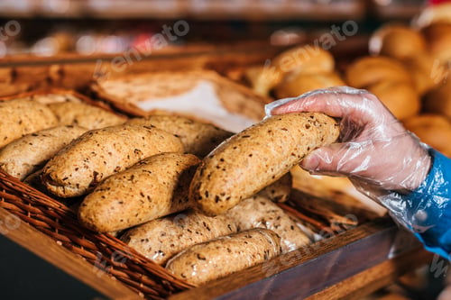 Preview: partial view of shopper taking loaf of bread in grocery shop