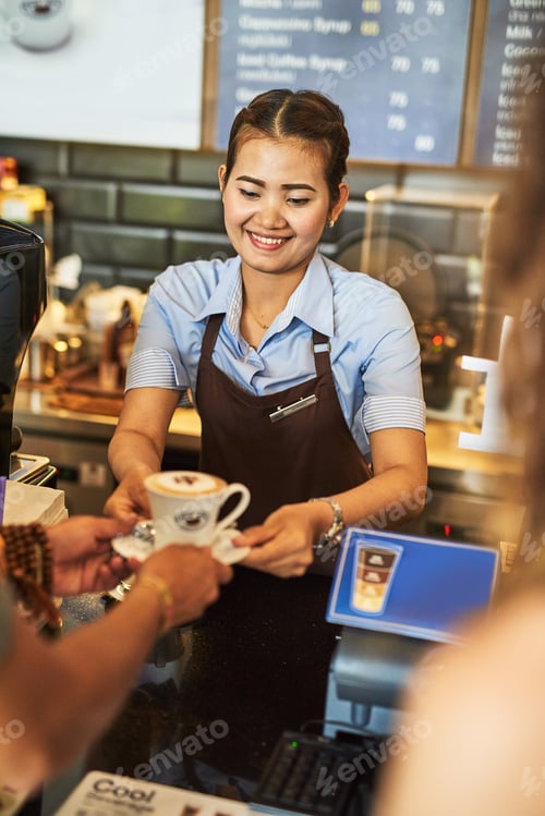 Preview: Brewed with care. Shot of a happy young barista working behind the cash register in a coffee shop.