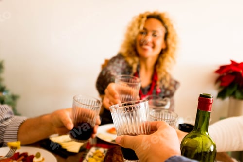 Preview: close up of hand of man holding a glass with wine and clinking with other three people eating
