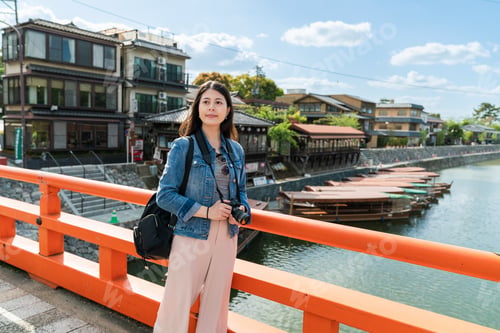 Preview: lady looking at scenery on red uji bashi bridge