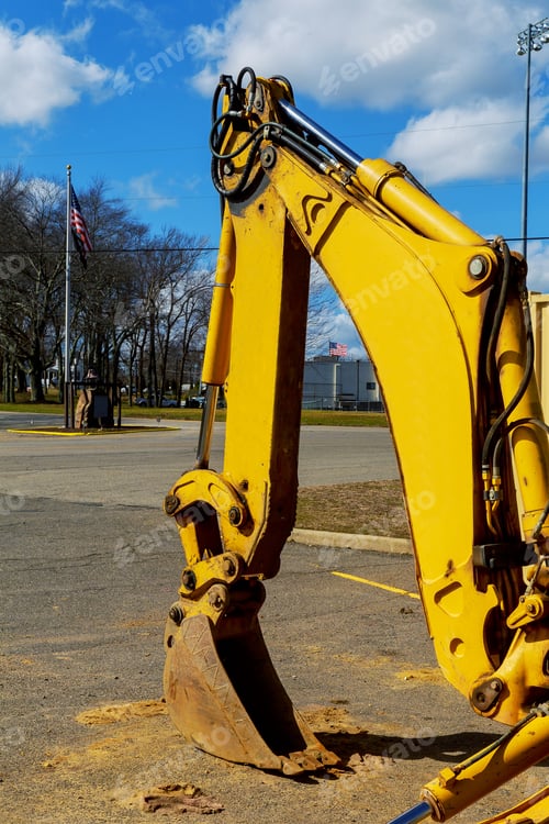 Preview: Excavator standing in sandpit with raised bucket over cloudscape sky