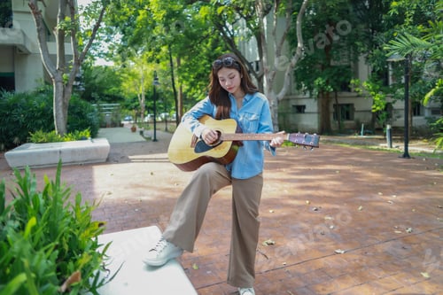 Preview: Young Woman Playing Acoustic Guitar in Serene Outdoor Public Space, Creating Calm and Artistic Vibe