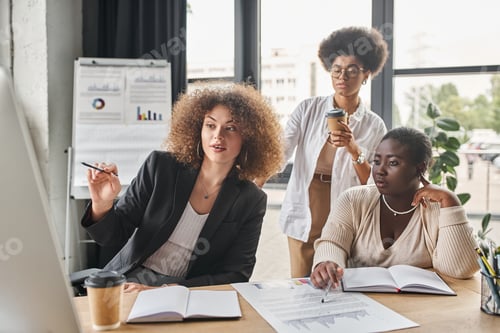 Preview: businesswoman pointing at computer monitor near african american colleagues in office, teamwork