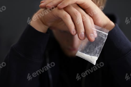 Preview: Criminal holding plastic bag with drug, closeup