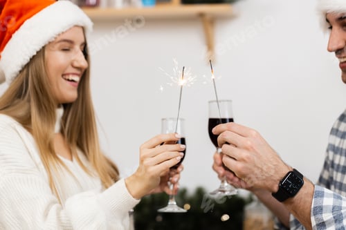 Visualização: Jovem casal com chapéus de Papai Noel bebendo vinho e comemorando o Natal