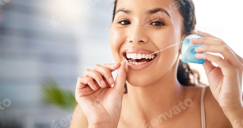 Preview: Dental hygiene is a priority. Shot of a young woman flossing her teeth at home.