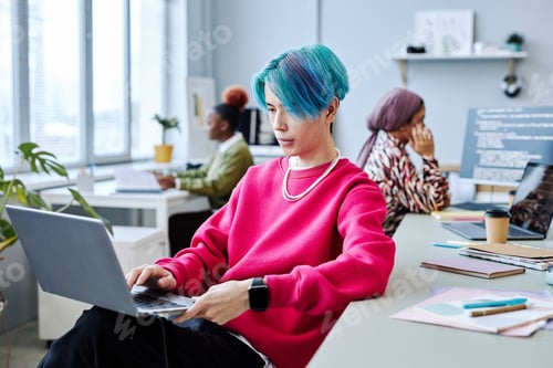 Preview: Asian young man using laptop in modern office, magenta accent