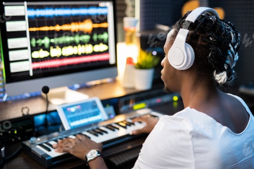 Preview: Young musician in headphones looking at sound waveforms on computer screen
