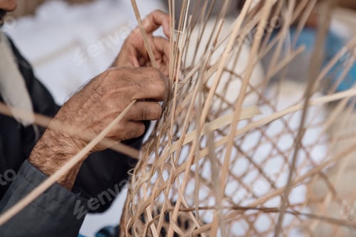 Preview: Old man is knitting weaving traditional basket from palm leaves, hands in frame