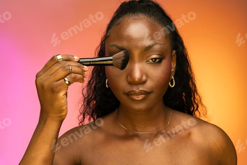 Preview: Beautiful African American lady closing her eye by makeup brush, isolated on colorful background