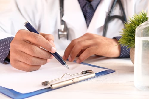 Preview: doctor hand writing prescription on desk, close up.
