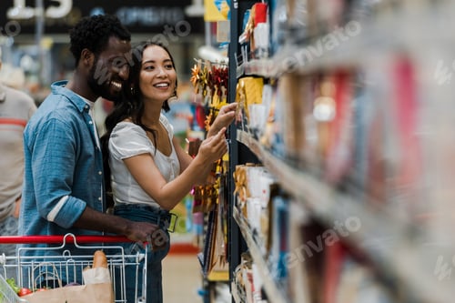 Preview: selective focus of cheerful african american man standing with asian woman pointing with finger at