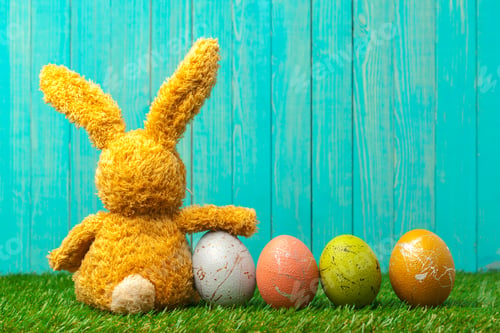Preview: Soft bunny with colorful eggs against a blue wooden background during Easter time