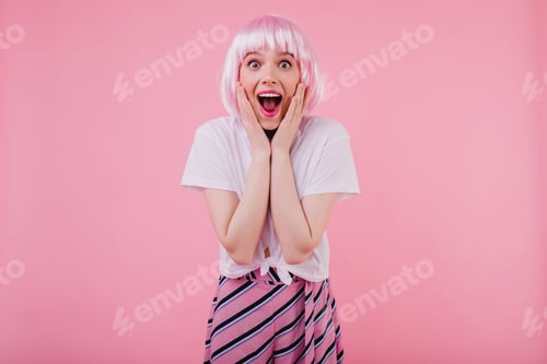 Preview: Good-humoured female model wears pink peruke expressing surprised emotions. Studio shot of pretty c