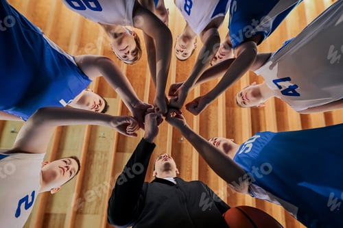 Preview: Low angle view of junior basketball team and coach stacking hands.