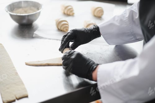 Preview: Baker rolling dough for croissants in a bakery
