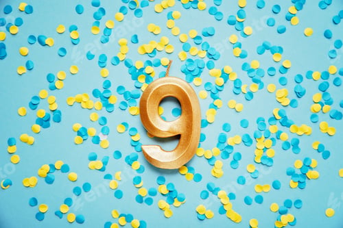 Preview: Number 9 nine golden celebration birthday candle on yellow and blue confetti Background.