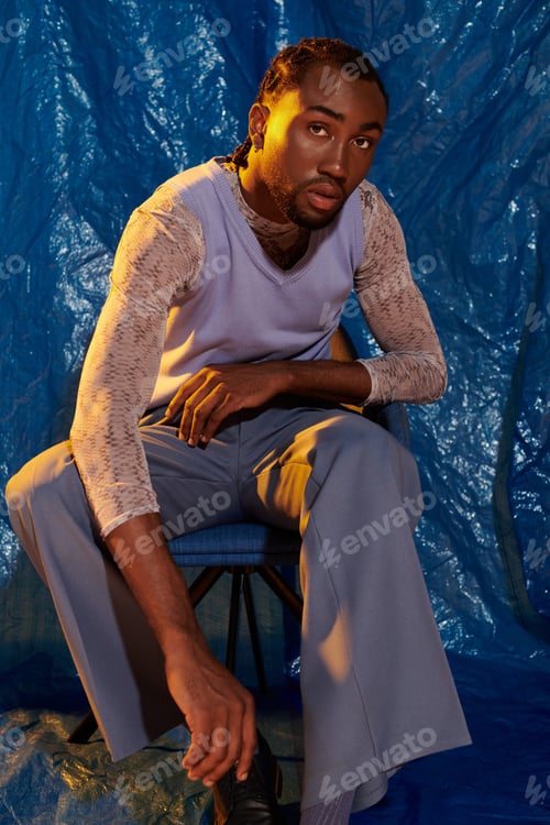Preview: Striking portrait of a handsome young man with a captivating expression against a blue backdrop