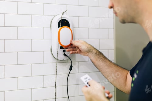 Preview: Man washes the white tiles on the walls in the bathroom with a gadget - a window cleaner