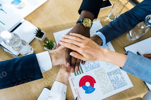 Preview: top view of multicultural men and women putting hands together near charts and graphs