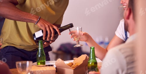 Preview: Close Up Of Man Pouring Wine For Friends Waiting For Takeaway Meal At Home
