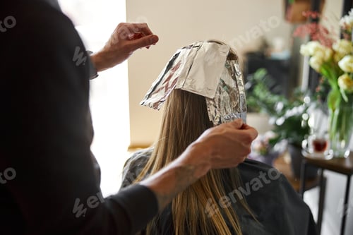 Preview: Confident male stylist is dyeing hair of blond caucasian female client
