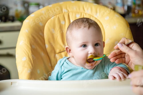 Preview: Little baby is eating broccoli vegetable puree. Selective focus.