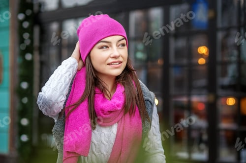 Preview: Beautiful brunette woman walking around the city in winter. Pink