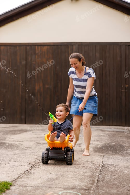 Preview: Mother having fun pushing child in toy truck